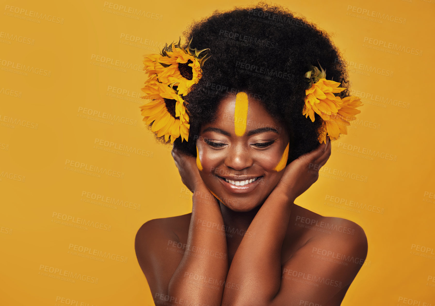 Buy stock photo Beautiful woman, sunflowers in hair and make up on face in studio for cosmetics, afro care and empowerment. Happy, black lady and yellow paint on forehead for summer, spring or warmer weather 