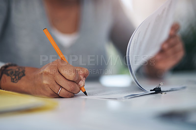 Buy stock photo Cropped shot of an unrecognizable businesswoman sitting alone in her office and writing on paperwork