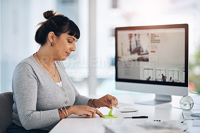 Buy stock photo Cropped shot of an attractive young businesswoman sitting alone in her office and using post-its to make notes