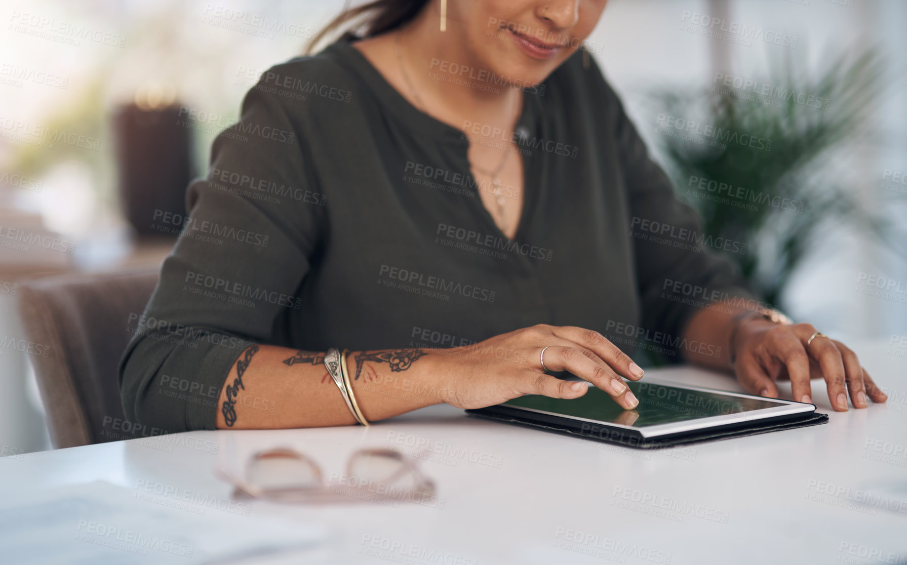 Buy stock photo Cropped shot of an unrecognizable businesswoman sitting alone in her office and using a tablet