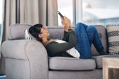 Buy stock photo Full length shot of an attractive young woman lying down in her living room alone and using her cellphone