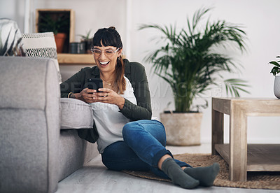 Buy stock photo Full length shot of an attractive young woman sitting in her living room alone and using her cellphone