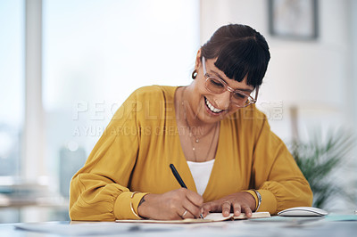 Buy stock photo Cropped shot of an attractive young businesswoman sitting alone in her office and writing in a notebook