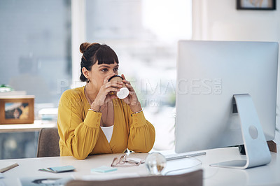 Buy stock photo Cropped shot of an attractive young businesswoman sitting in her office and enjoying a coffee while using her computer