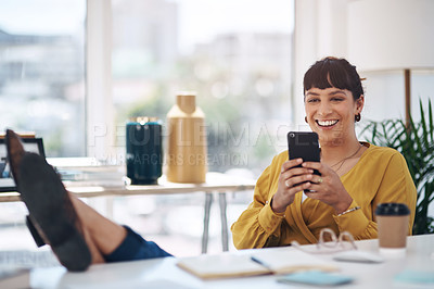Buy stock photo Cropped shot of an attractive young businesswoman sitting with her feet up in her office and using her cellphone