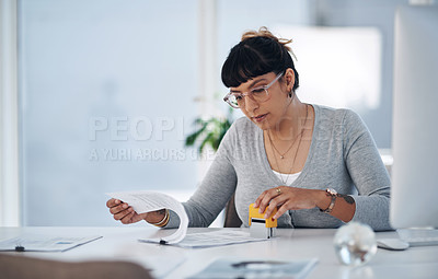 Buy stock photo Cropped shot of an attractive young businesswoman sitting alone in her office and reading through paperwork