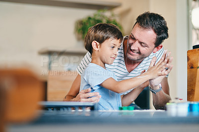 Buy stock photo Shot of an adorable little boy giving his father a high five while baking together at home