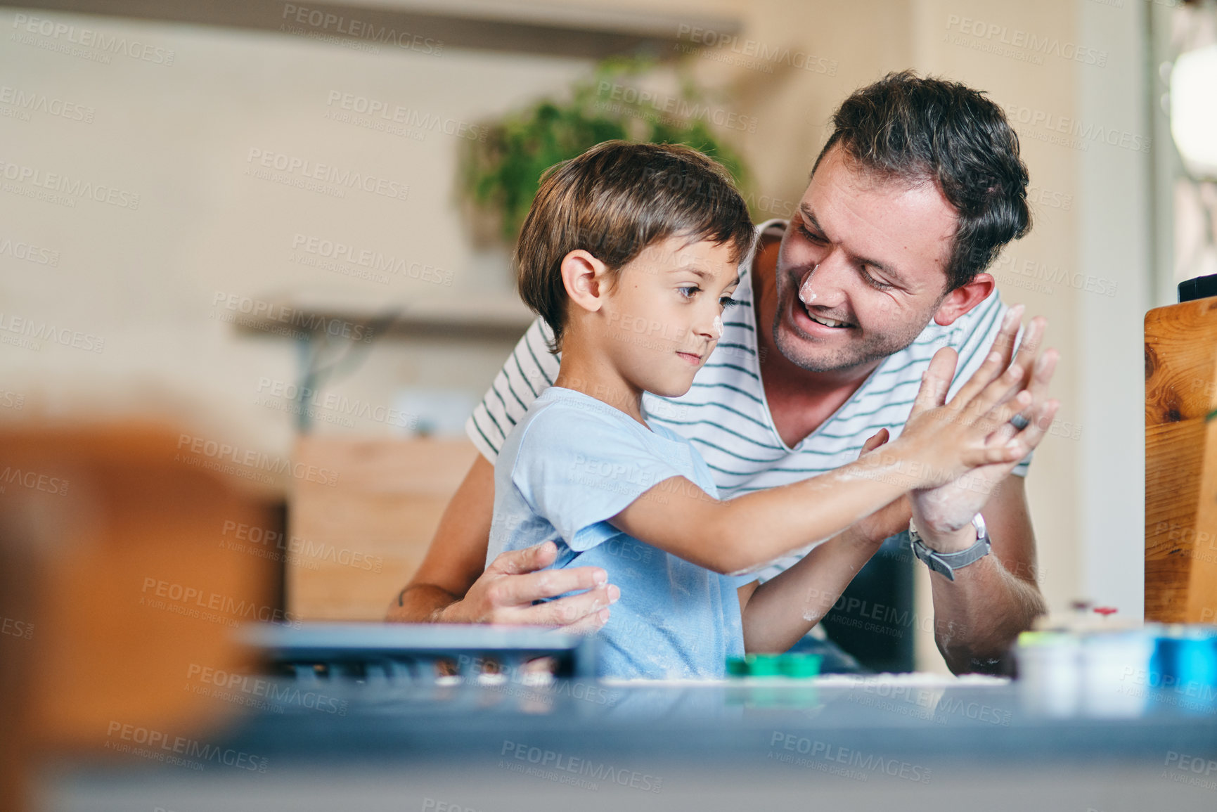 Buy stock photo Shot of an adorable little boy giving his father a high five while baking together at home