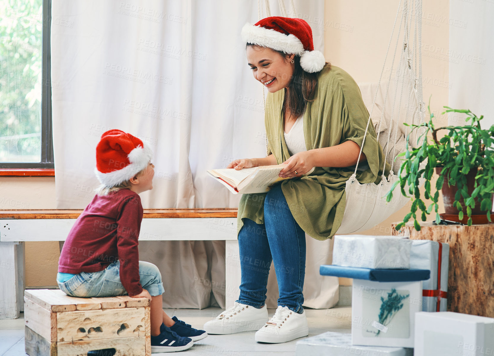 Buy stock photo Shot of a young woman reading a book with her adorable son at Christmas