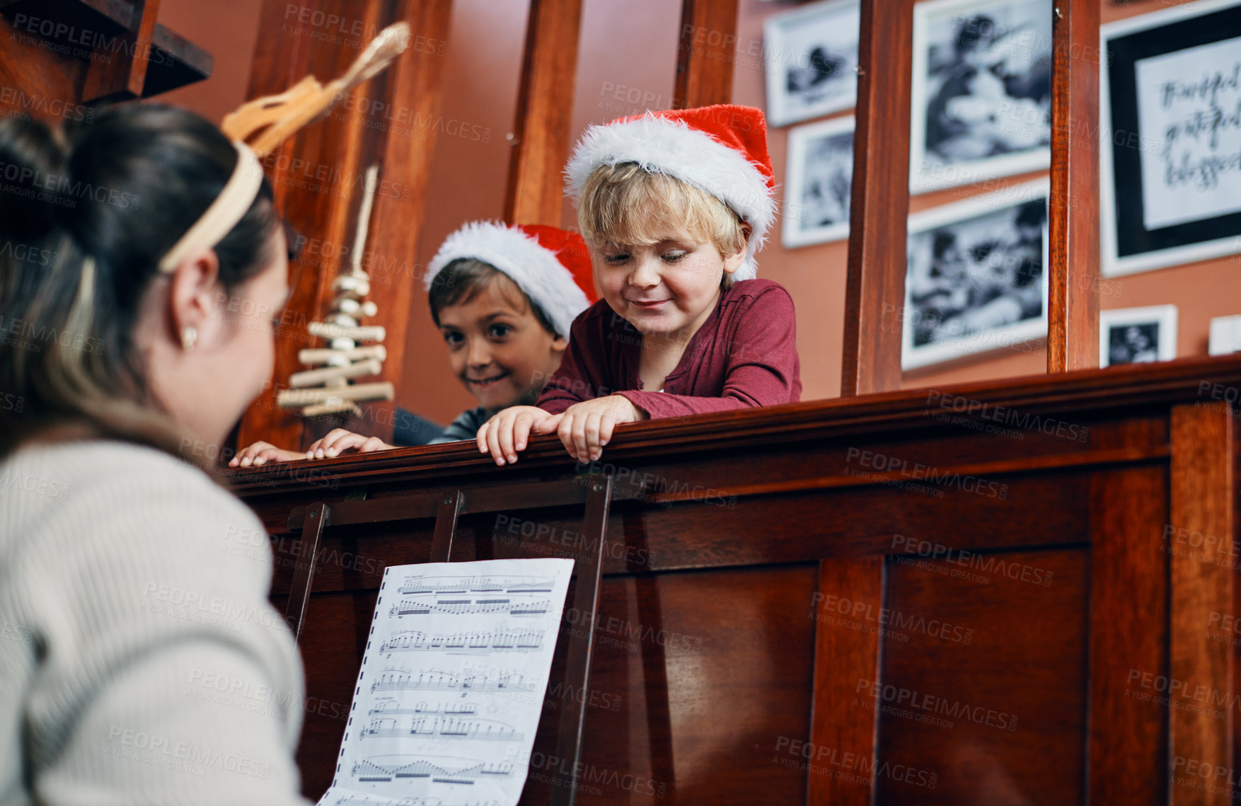 Buy stock photo Shot of a young woman playing the piano for her sons at Christmas