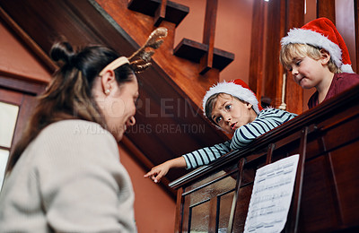 Buy stock photo Shot of a young woman playing the piano for her sons at Christmas