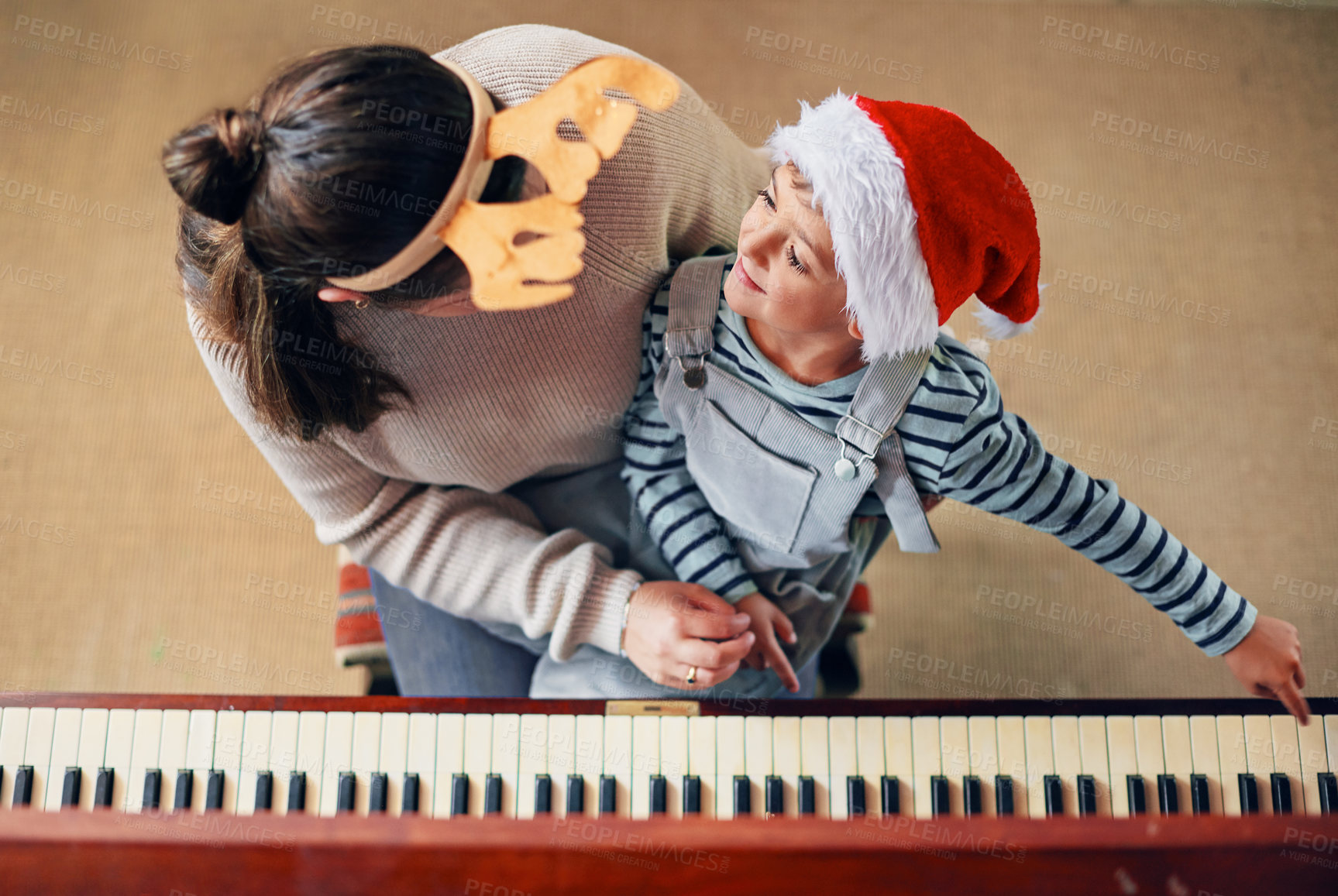 Buy stock photo Shot of an adorable little boy playing the piano with his mother at Christmas