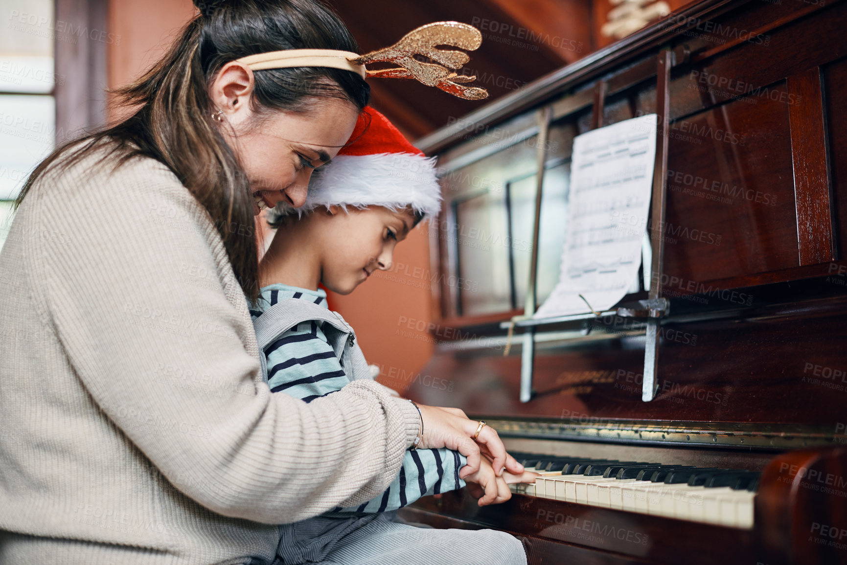 Buy stock photo Shot of an adorable little boy playing the piano with his mother at Christmas