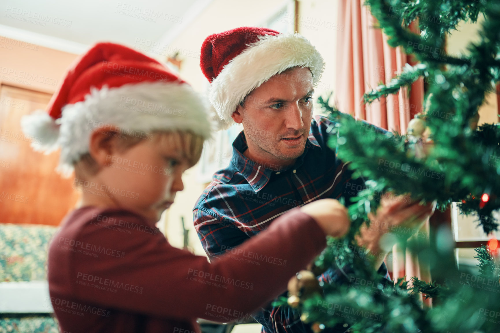 Buy stock photo Shot of an adorable little boy decorating the Christmas tree with his father at home