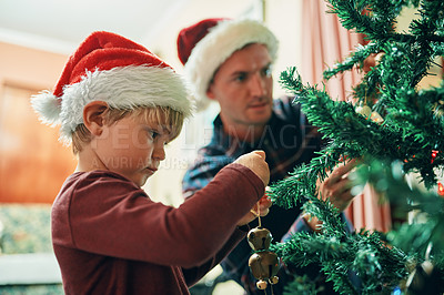 Buy stock photo Shot of an adorable little boy decorating the Christmas tree with his father at home