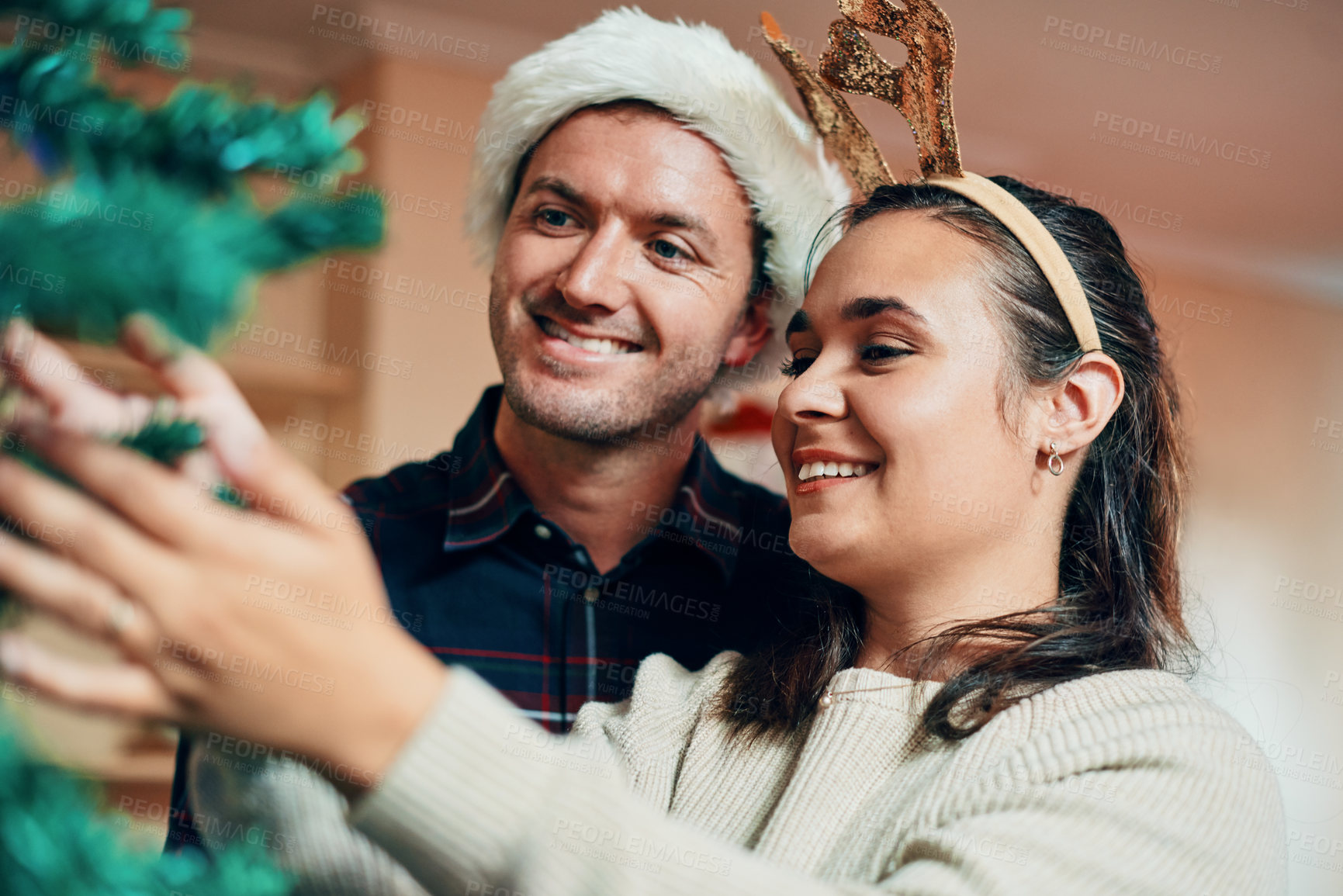 Buy stock photo Shot of a happy young couple decorating their Christmas tree together at home