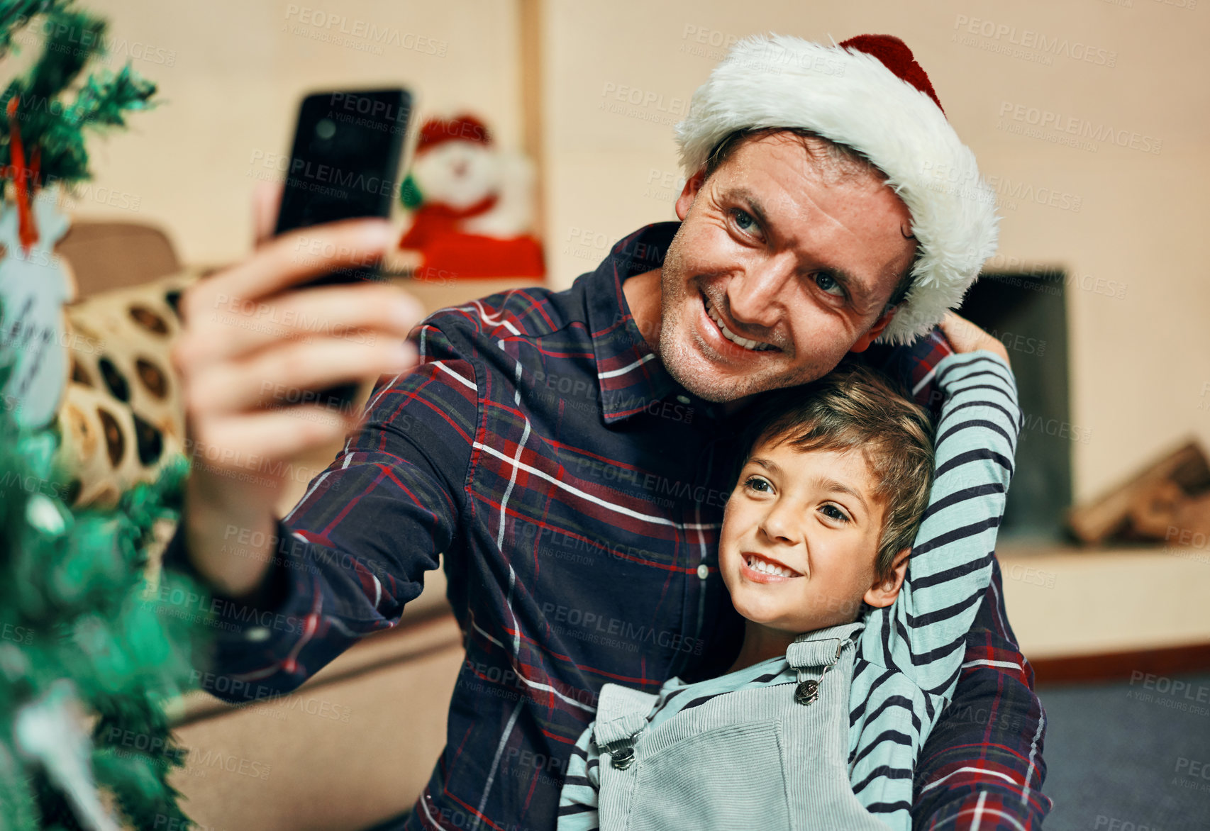 Buy stock photo Shot of an adorable little boy taking selfies with his father during Christmas at home