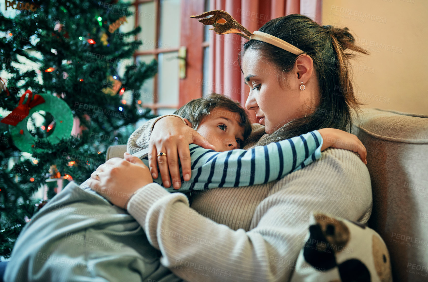 Buy stock photo Shot of an adorable little boy relaxing on the sofa with his mother at Christmas