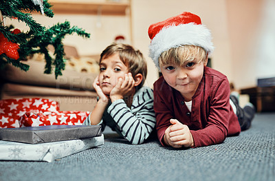 Buy stock photo Shot of two adorable little boys lying down next to the Christmas tree at home