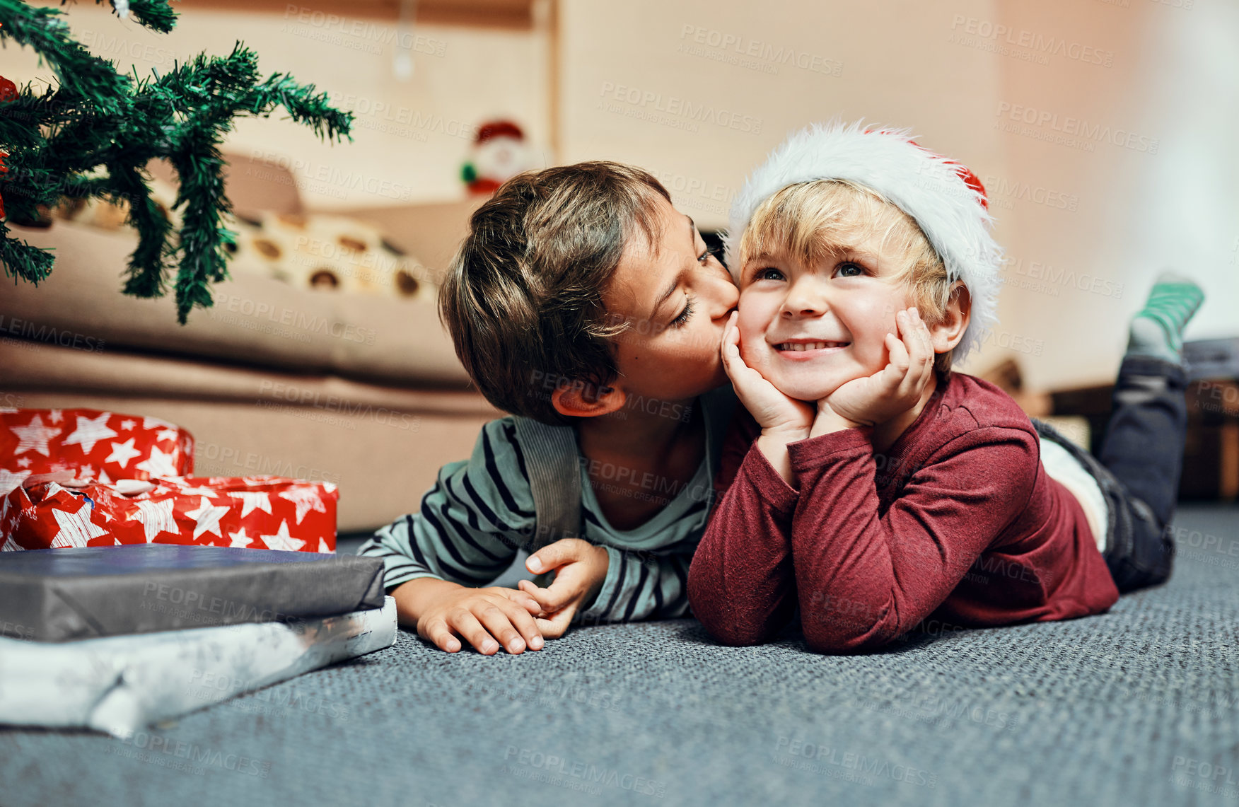 Buy stock photo Shot of an adorable little boy giving his brother a kiss while waiting to open their Christmas presents
