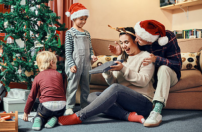Buy stock photo Shot of a young woman receiving a Christmas present from her family