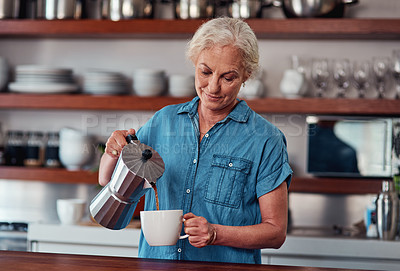 Buy stock photo Cropped shot of an attractive senior woman pouring herself a cup of coffee while standing in the kitchen