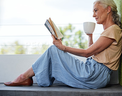 Buy stock photo Full length shot of an attractive senior woman enjoying a cup of coffee while reading a book outside on her balcony at home