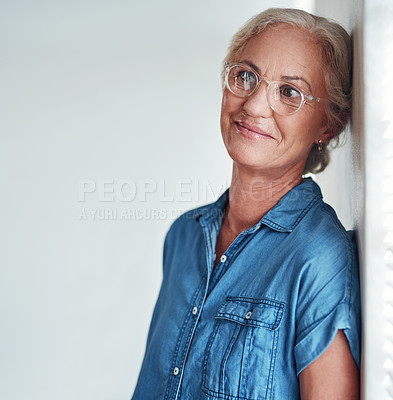 Buy stock photo Cropped shot of an attractive senior woman leaning against a wall and looking contemplative while posing in front of a grey background at home