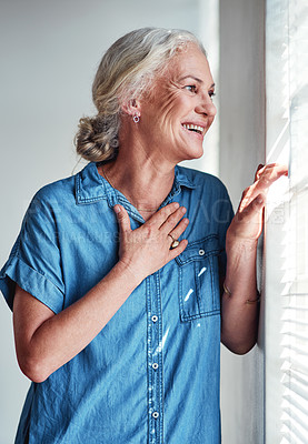Buy stock photo Cropped shot of an attractive senior woman looking out of her window at home