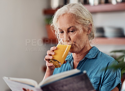 Buy stock photo Cropped shot of an attractive senior woman enjoying a glass of orange while reading a book in her kitchen at home
