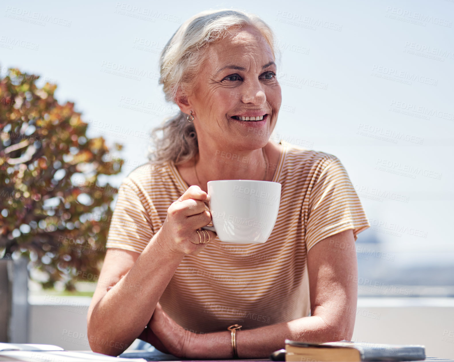 Buy stock photo Cropped shot of an attractive senior woman enjoying her breakfast while sitting outside on the balcony at home