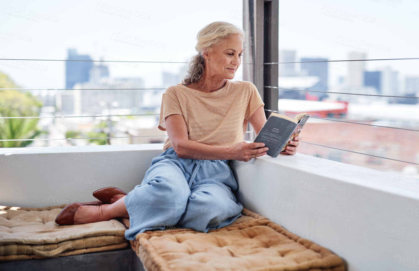 Buy stock photo Senior woman, relax and book on balcony for retirement, reading and peace in apartment. Mature, female person and novel in morning or home for calm or zen, knowledge and smile for story or fantasy