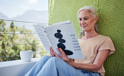 Buy stock photo Cropped shot of an attractive senior woman enjoying a cup of coffee while reading a book outside on her balcony at home