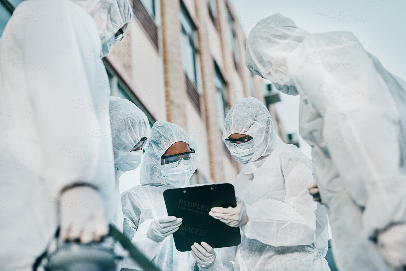 Buy stock photo Shot of a group of healthcare workers wearing hazmat suits working together during an outbreak in the city