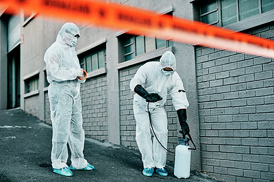 Buy stock photo Shot of two healthcare workers wearing hazmat suits working together during an outbreak in the city
