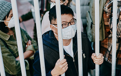 Buy stock photo Sick, trapped young covid patient stuck in the city feeling like a prisoner, wearing a medical face mask. Foreign asian man in a crowd during a pandemic. Male following city healthcare safety rules.