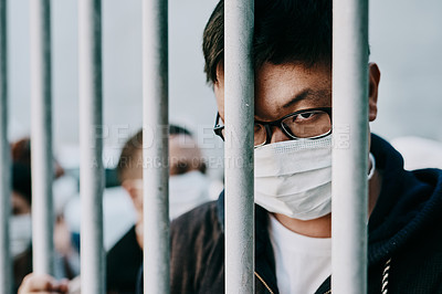 Buy stock photo Depressed, upset or sad covid patient stuck in the city feeling like a prisoner, wearing a medical face mask. Foreign asian man in a crowd during pandemic holding area following city healthcare rules