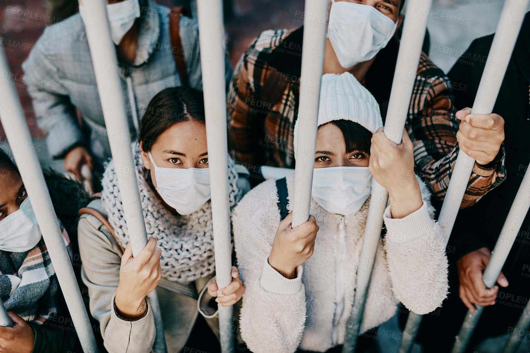 Buy stock photo Covid travel ban, lockdown or border control to prevent spread of pandemic virus, contagious disease or illness. Portrait of prisoners in masks facing racism and discrimination behind locked gate