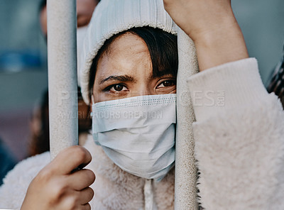 Buy stock photo Shot of a young woman wearing a mask while stuck behind a gate in a foreign city