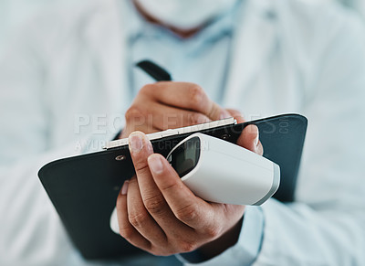 Buy stock photo Cropped shot of a doctor holding an infrared thermometer and writing notes during an outbreak