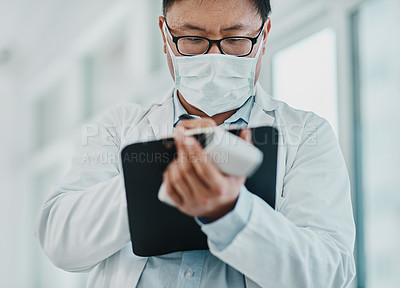 Buy stock photo Shot of a doctor holding an infrared thermometer and writing notes during an outbreak