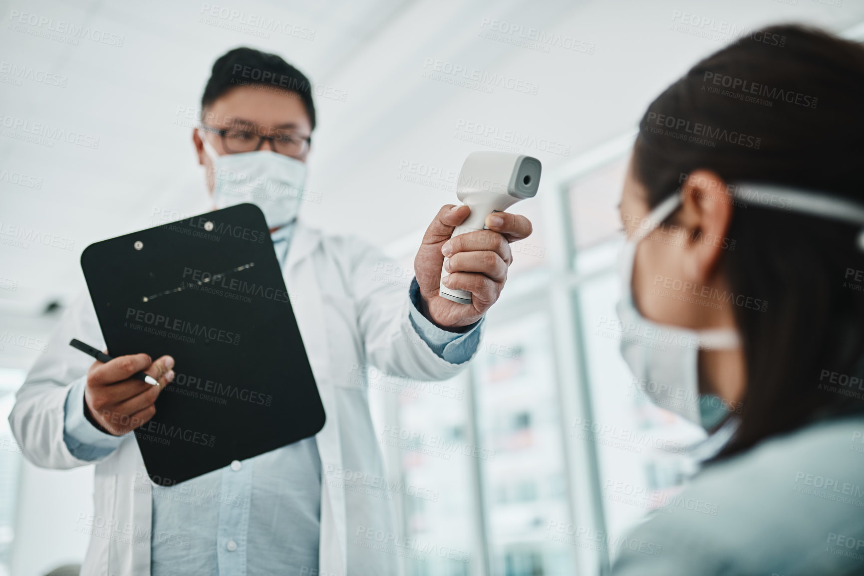 Buy stock photo Doctor scanning the temperature of a patient for corona with a digital thermometer. Health care professional consulting with a concerned female about flu symptoms during the covid virus pandemic