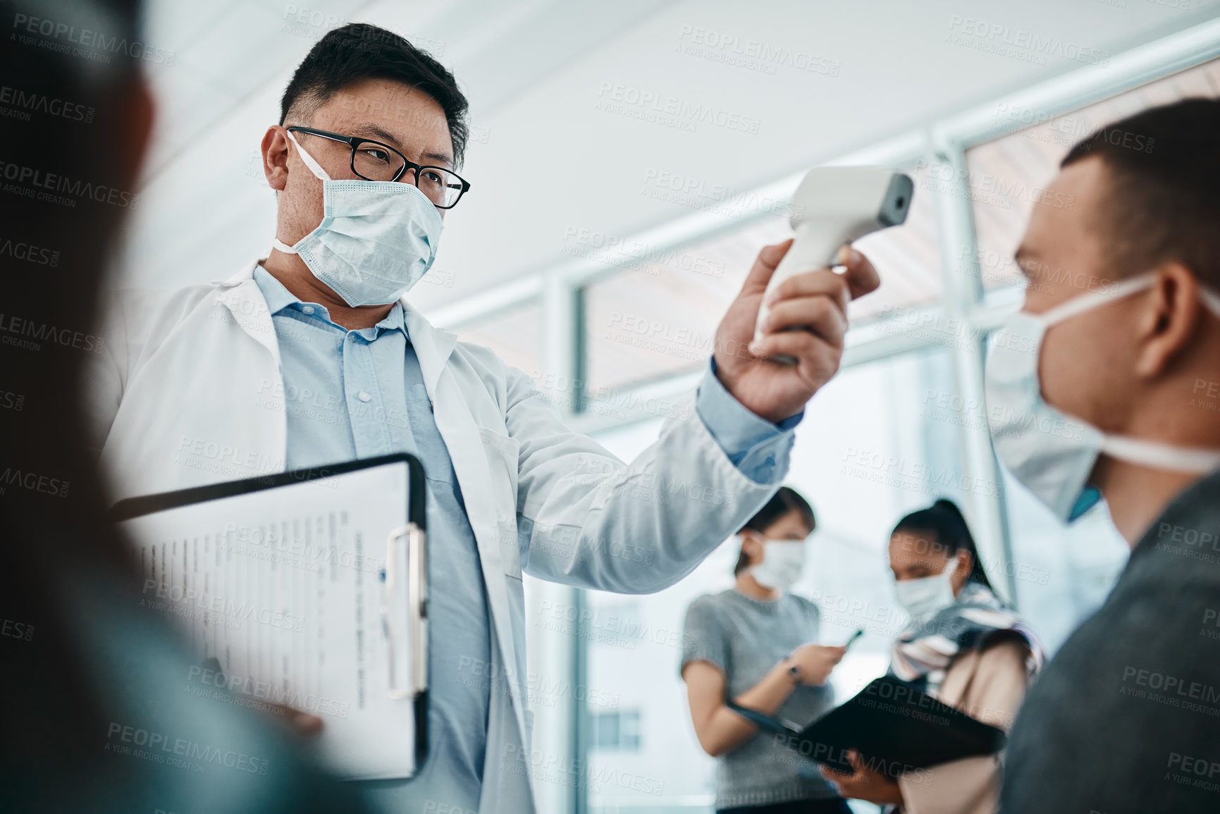 Buy stock photo Doctor testing covid temperate in hospital appointment to prevent the spread of the virus. Healthcare compliance worker with health insurance document and face mask checking or scanning patient head