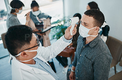Buy stock photo Shot of a young man getting his temperature taken with an infrared thermometer by a healthcare worker during an outbreak