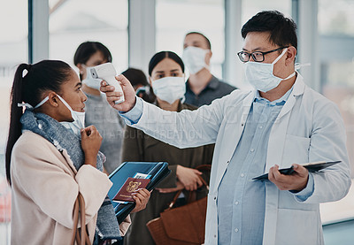 Buy stock photo A travel healthcare worker testing covid temperature at the airport using an infrared thermometer. Medical professional doing a coronavirus check on a woman at an entrance to prevent the spread