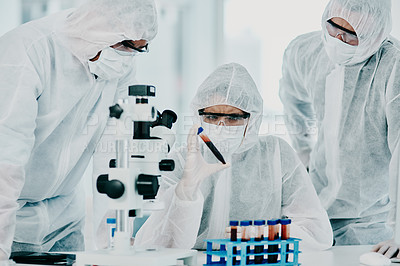 Buy stock photo Group of scientists conducting medical research in hazmat suits and protective gloves, for coronavirus cure in a laboratory. Researchers conducting experiments and examining test tube for results.