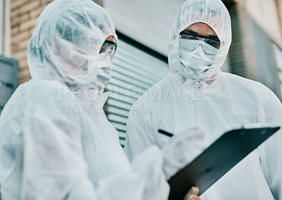 Buy stock photo Healthcare workers wearing protective hazmat suits writing a medical report about covid cases or statistics. First responders filling in a form after doing a safety health check for coronavirus 