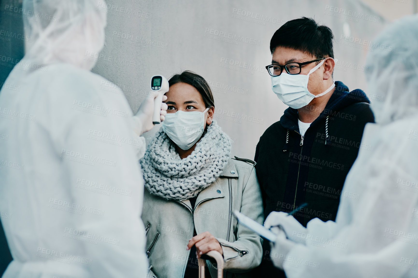 Buy stock photo Traveling couple getting a covid temperature scan at the border with medical security doing screening test for safety during pandemic. Foreign people or traveler arriving at an airport with face mask