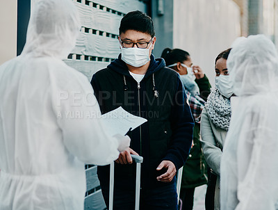 Buy stock photo Shot of a young man talking to a healthcare worker in a hazmat suit during an outbreak