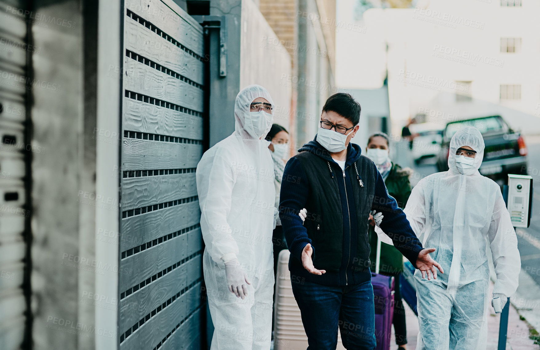 Buy stock photo Man breaking covid regulation getting taken away or arrested by healthcare workers wearing hazmat protective suits. Male removed for not following the rules or restrictions of coronavirus pandemic